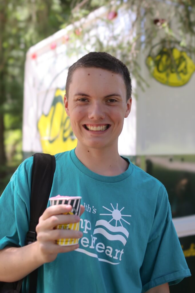 Boy holidng up a Del's lemonade in front of a Del's truck.