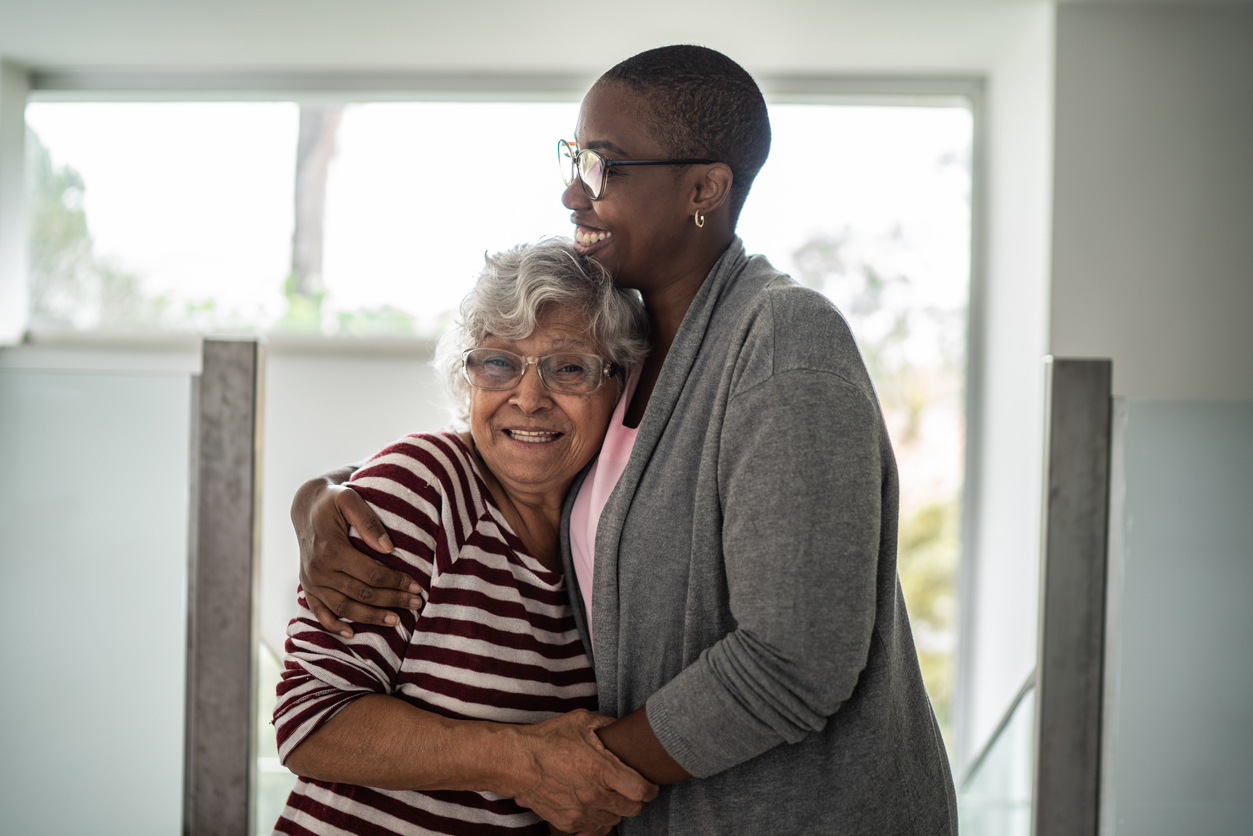 Nurse and senior woman embracing at home