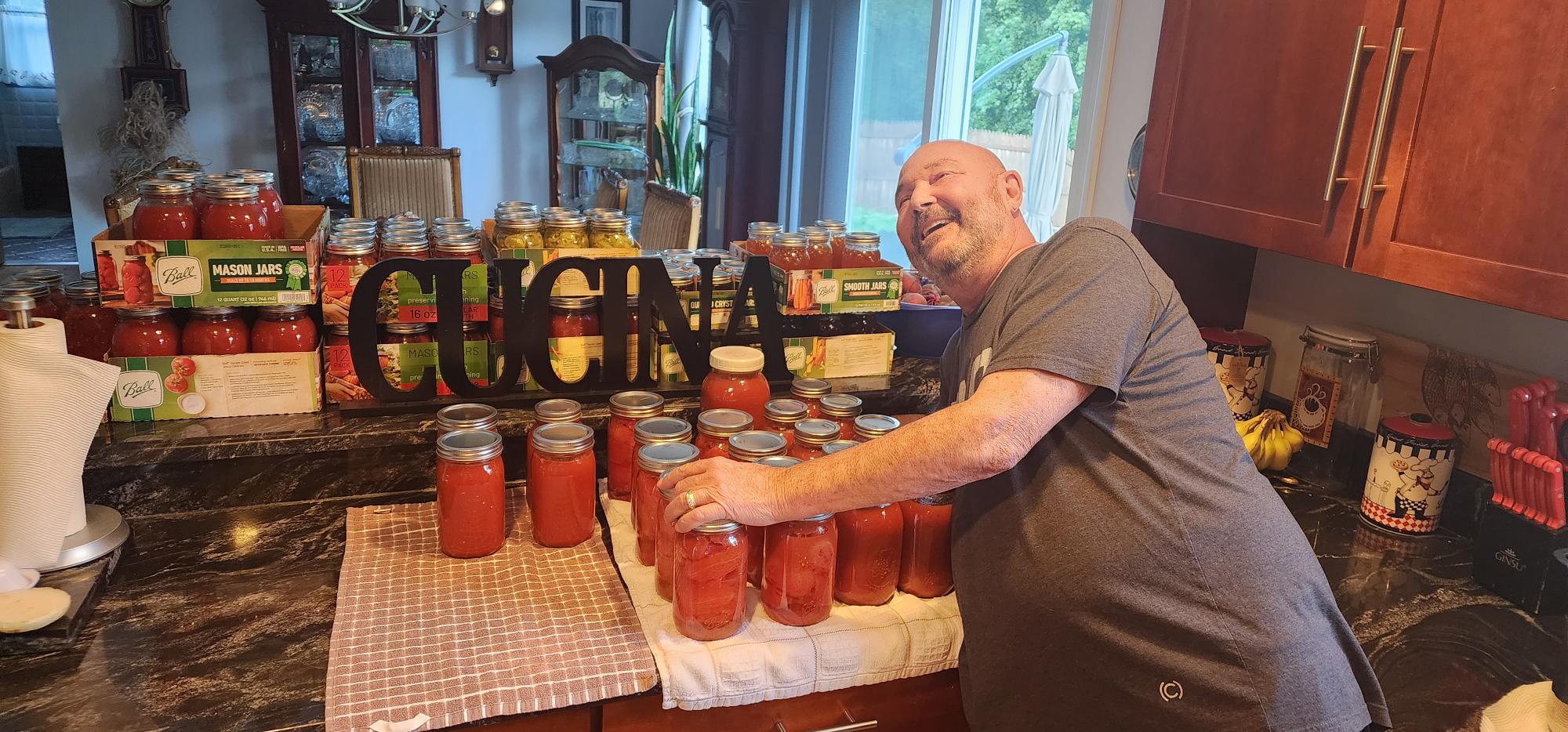 Man standing with his many jars of tomato sauce