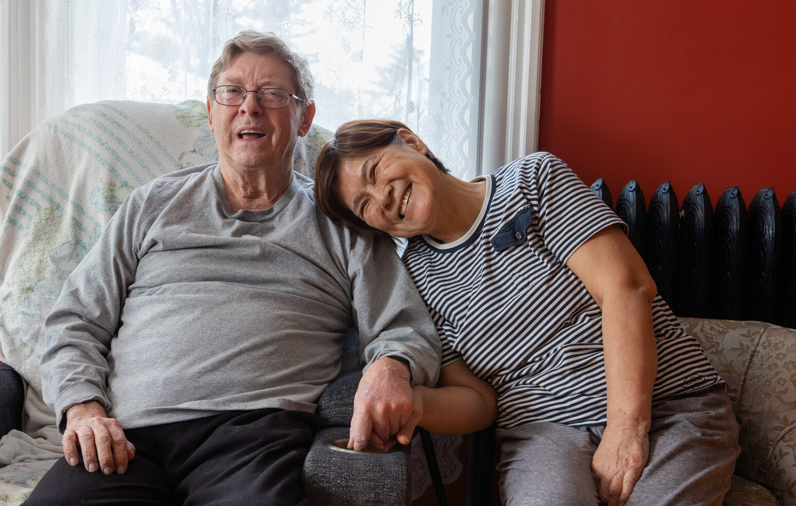 A woman affectionately rests her head on her husbands shoulder, both are warmly smiling at the camera