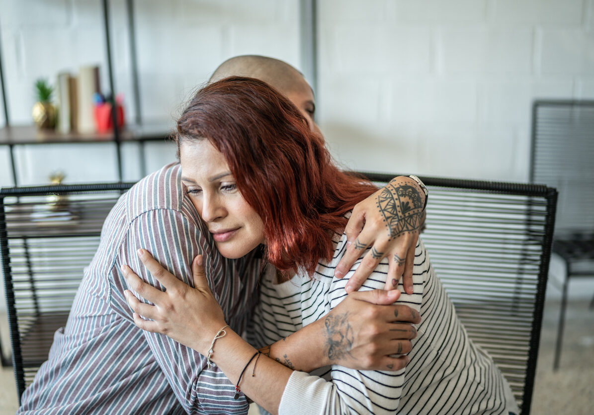 woman with red hair being comforted by a man