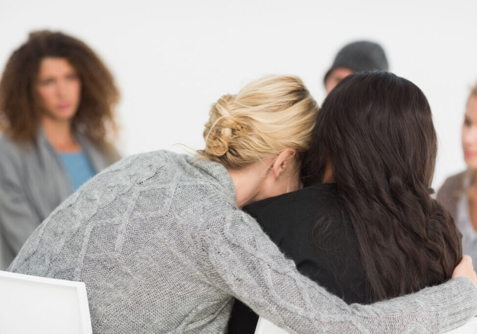 Women embracing in rehab group at therapy session